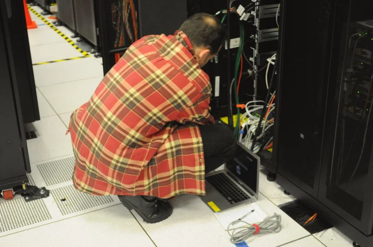 Technician with a laptop working at a server rack